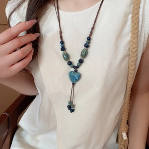 Gros plan du pendentif cœur en céramique bleue avec perles vernies sur collier