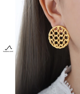 Detail of vintage hollow round woven gold stainless steel earrings on a model