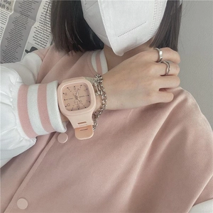 Close-up of a pink square digital sports watch paired with a silver chain bracelet on a wrist