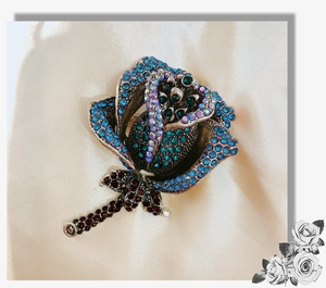 Close-up of rose brooch with colorful rhinestones on champagne satin background