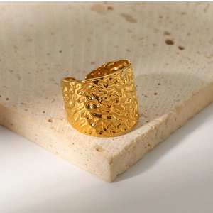 Macro detail of gold-plated textured lava ring on beige travertine stone display