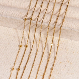 Selection of diverse 18k gold plated stainless steel chains on a beige textured fabric