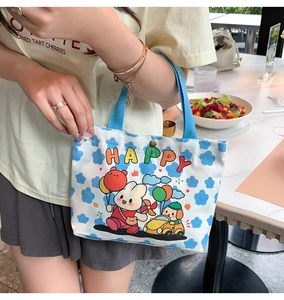 Close-up of a white canvas tote bag with blue cloud print and cartoon animal patterns