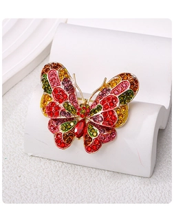 Close-up of vibrant butterfly brooch with colorful crystals on a white pedestal