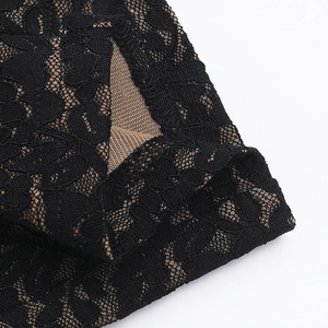 Close-up detail of sheer black floral lace fabric with a nude mesh inner lining