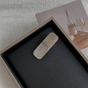 Detail of a rectangular lighter case with iridescent shell texture on a display tray
