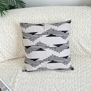 Detail of grey cotton linen pillowcase with black geometric patterns on a white sofa