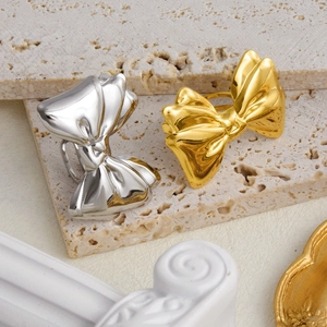 Detailed view of gold and silver bow rings with ribbon textures on a stone base
