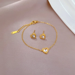 Golden titanium steel heart jewelry set with white zircons on soft satin background