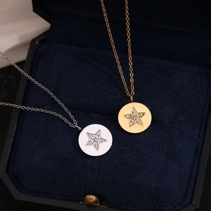 Détail de colliers avec pendentifs ronds étoile or et argent dans un écrin à bijoux bleu