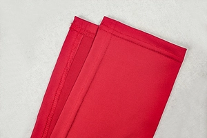 Detail eines roten ärmellosen Kleides mit präziser Doppelnaht und Stoffstruktur im Fokus