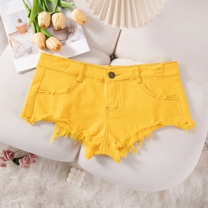 Pantaloncini di jeans gialli con orlo a frange e dettagli strappati in uno scatto flat lay