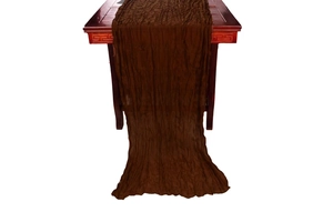 Detail shot of brown crinkle gauze table runner showing textured fabric on wooden table