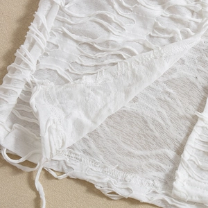 Macro detail of white distressed fabric with fringe and hollow-out texture on summer dress