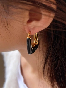 Close-up of elegant U-shaped 18K gold plated earrings with black enamel inlay on model
