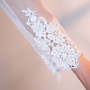 Detail showing elegant lace floral embroidery and sheer tulle on the long sleeves of the gown