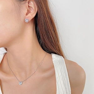 Close-up of sparkling heart-shaped zircon earrings and necklace set on a female model