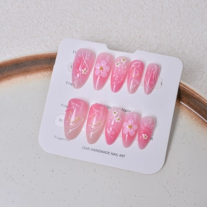 Detailed view of pink gradient press-on nails with 3D floral, butterfly, and pearl accents