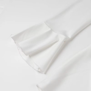 Détail du tissu en soie lisse et des volants sur la manche de cette robe blanche élégante