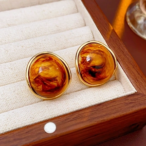 Close-up of vintage amber resin stud earrings with golden metallic rim in a jewelry box
