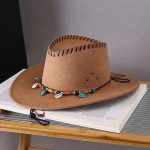 Brown western cowboy hat with ethnic beaded band and shell charms on wooden table