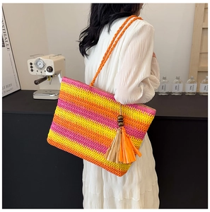 Detail of straw tote bag with rainbow stripes, rope handles and a large wood bead tassel