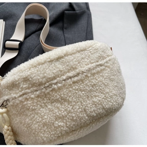 Detail showing soft white plush texture and beige adjustable fabric strap of the bag