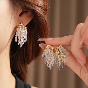 Boucles d'oreilles dorées avec cristaux marquise verts et franges sur un mannequin