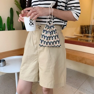 Detalle de una bolsa vintage de flores con cordones blancos sostenida por una modelo