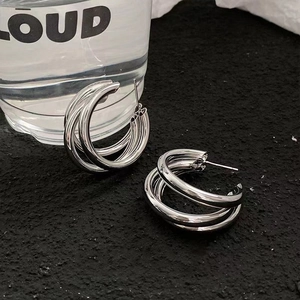 Close-up of silver-plated multi-layer spiral C-shaped hoop earrings on black texture