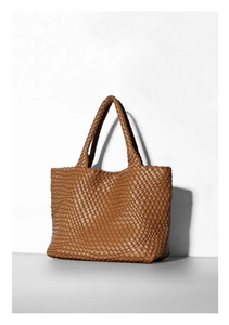 Close-up of brown woven tote bag showing intricate wide-strip leather texture and craftsmanship