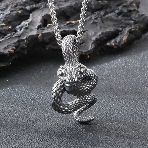 Detailed view of punk style stainless steel snake pendant on dark rock surface