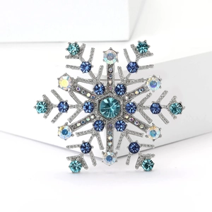Élégante broche flocon de neige argentée avec cristaux bleus sur fond blanc géométrique