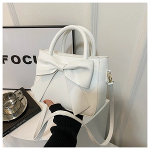 Detail of a white crossbody bag featuring a large decorative bow and elegant PU leather texture