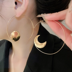 Detail of gold asymmetric sun and moon hoop earrings with handcrafted hammered texture