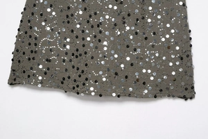 Macro del tessuto grigio con paillettes e ricami dettagliati neri e argento del vestito