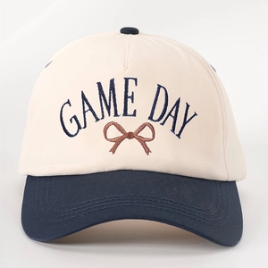 Close-up of GAME DAY embroidery and bow detail on the two-tone cotton baseball cap