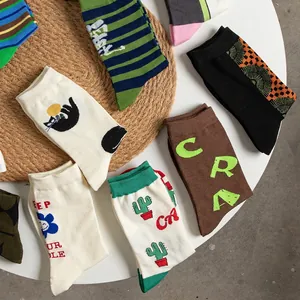 Assorted cotton crew socks with vibrant patterns displayed on a white table and straw mat