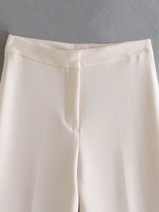 Detail of beige high-waist trousers showing waist design and hidden zipper closure