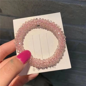 Close-up of pink faceted crystal beads on an elastic hair tie displayed on a white card