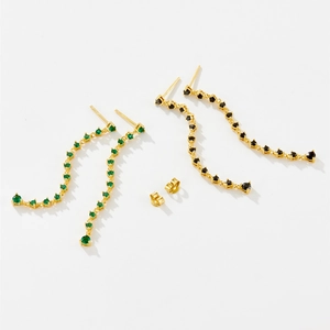 Detailed close-up of wavy gold tassel earrings featuring green and black zircon stones