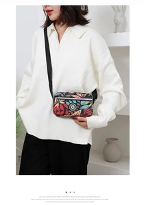Detail of floral Oxford fabric crossbody bag with adjustable strap on white sweater