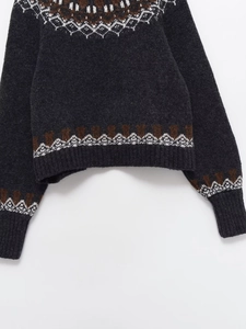 Dettaglio del maglione grigio Fair Isle con motivi bianchi e marroni su trama di lana