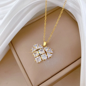 Close-up of golden hollow heart pendant with sparkling cubic zirconia on white silk cloth