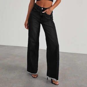 Détail du jean noir à taille haute et jambe large avec ourlets bruts effilochés