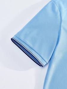 Détail de la manche d'un polo bleu clair avec bord-côte rayé bleu marine et blanc
