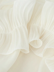 Macro shot of off-white chiffon fabric with pleated textures and layered ruffles details