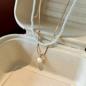 Detail view of 18k gold-plated double-layer pearl necklace with zircon pendant charm