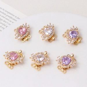 Close-up of heart-shaped gold jewelry clasps with pink and purple zircon stones