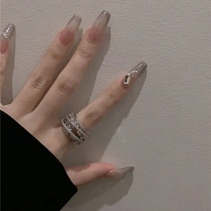 Close-up of silver multilayer zircon cross ring worn on finger with elegant lighting